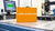 Bright orange laser calibration box on a precision worktable in a lab setting.